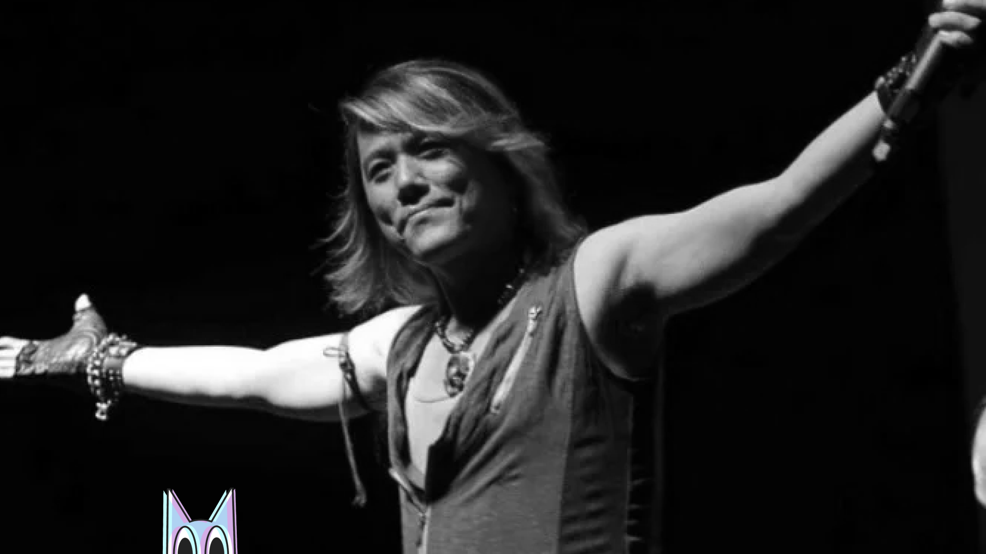 O cantor Nobuo "NoB" Yamada em uma performance no palco, com uma imagem de Seiya de Pégaso ao fundo, em homenagem ao seu legado.